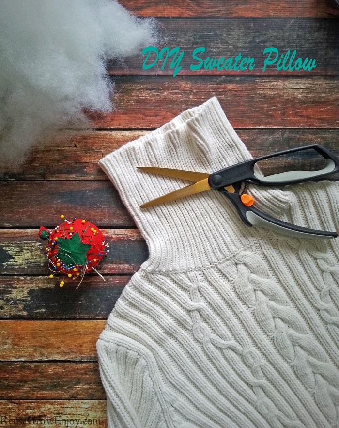 White sweater laying on wood background with cotton stuffing pin cushion. Text overlay at top that says DIY Sweater Pillow