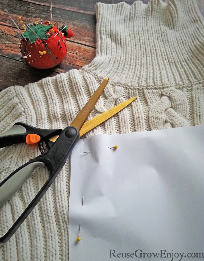 Paper pattern pinned to sweater with scissors laying on the side