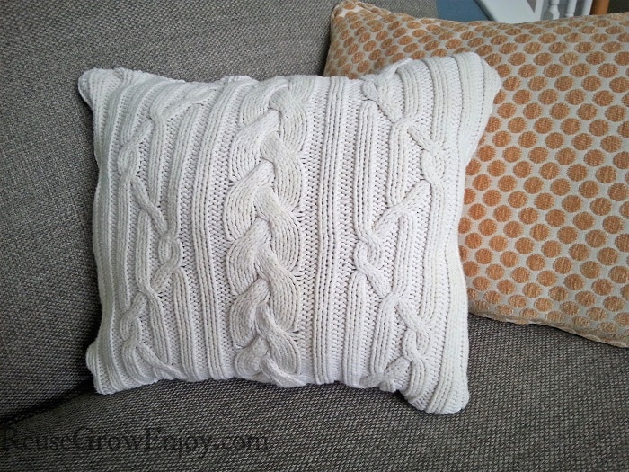 Finished white sweater pillow on couch with other pillows