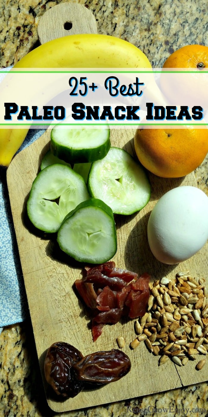 A wood cutting board with egg, jerky, sunflower seeds, dates, banana, cucumber slices and oranges with a text overlay that says - "25+ Best Paleo Snack Ideas"