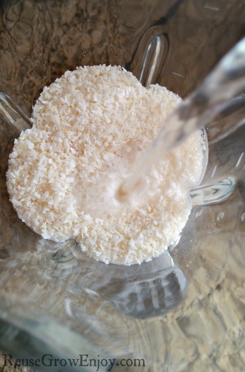 Boiling water being poured over dry coconut in blender