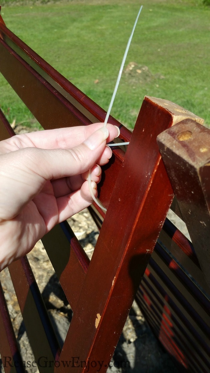 Hand attaching zip tie to top of rails.