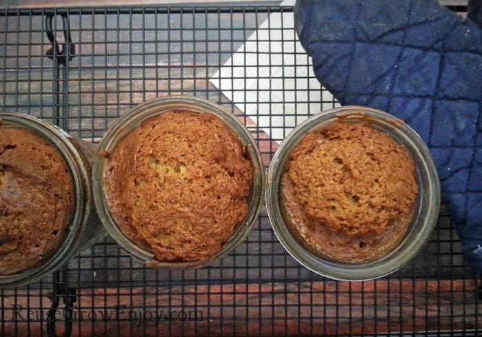 Banana bread baked in mason jar sitting on cooling rack with pot holder.