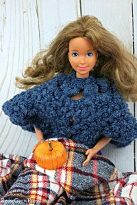 Barbie holding pumpkin on lap with blanket