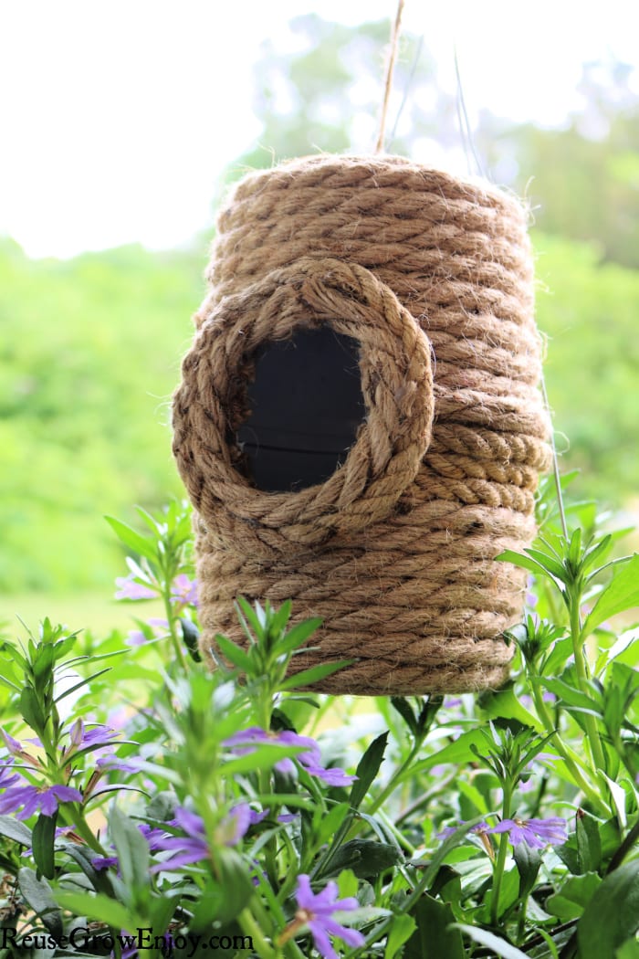 Beehive DIY birdhouse hanging over purple flowers