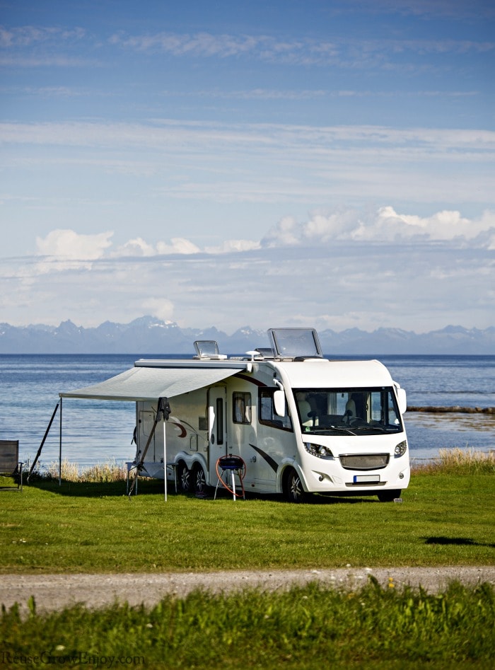 RV camping by water with green grass around it.