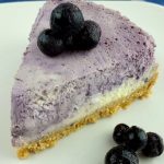 Slice of Marble Blueberry Instant Pot Cheesecake on a white plate with fresh blueberries on top and to the side.