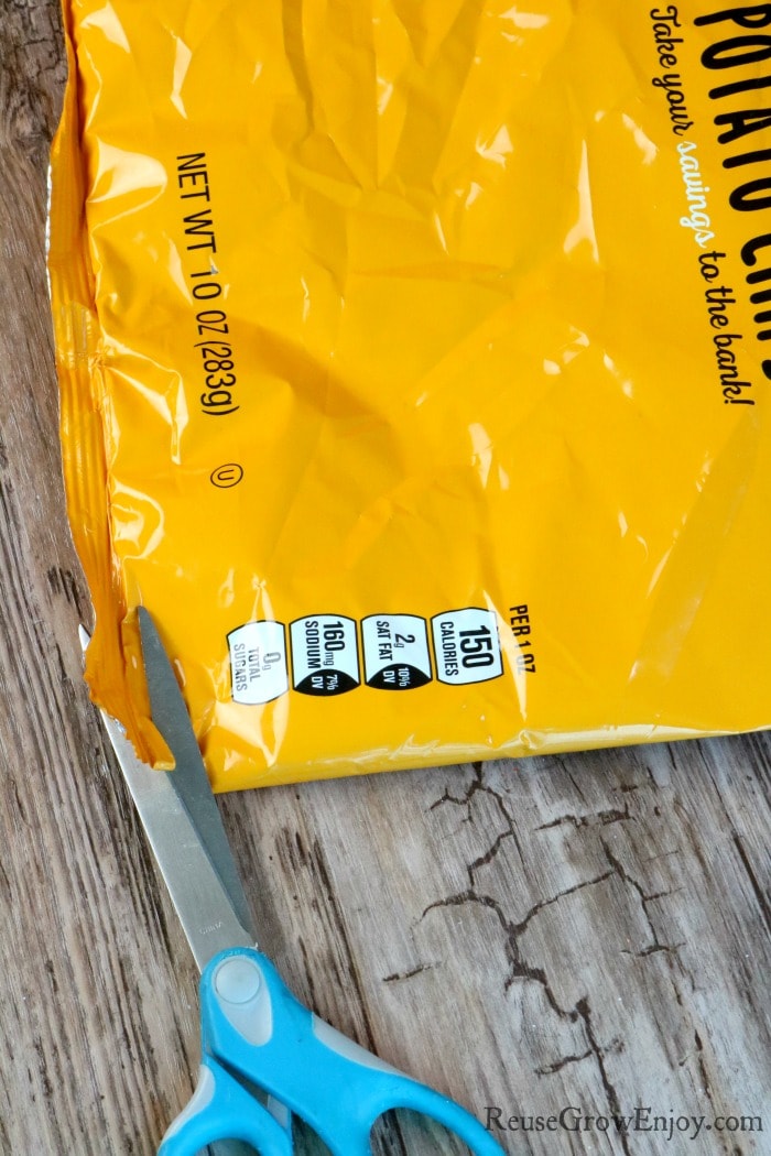 Scissors cutting bottom edge of chip bag off