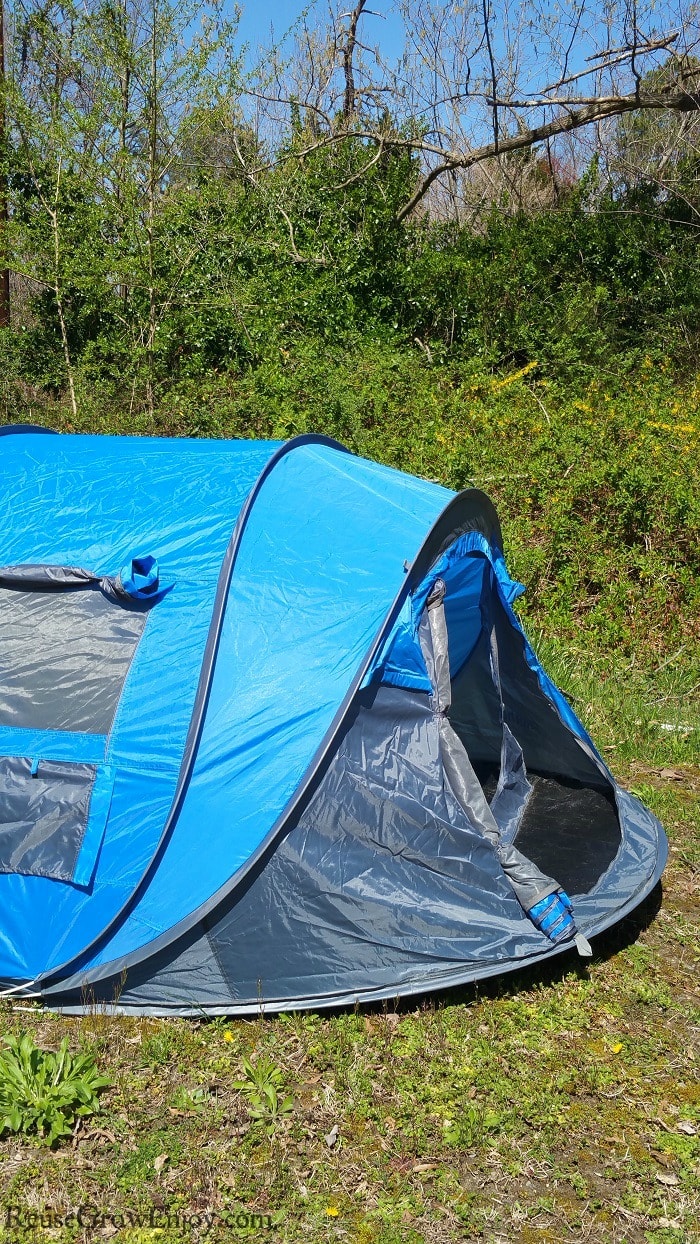 Blue tent with vines and trees in background.