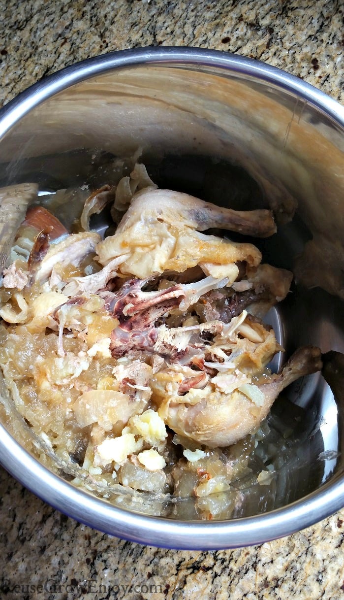 Leftover chicken bones in inner pot of an Instant pot sitting on a granite counter.