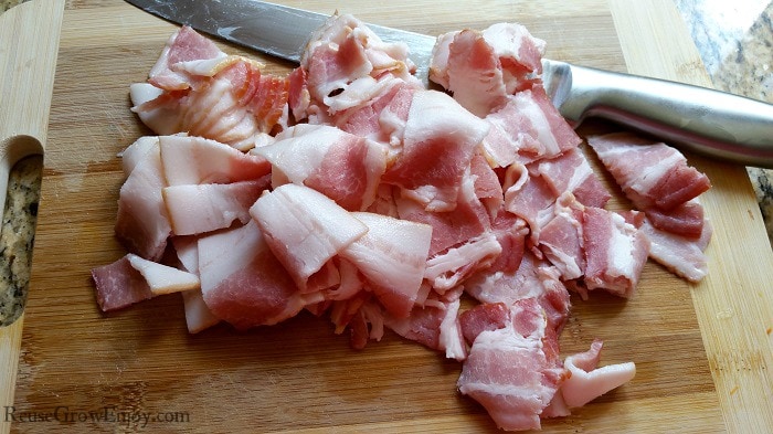 Bacon cut into chunks on cutting board with knife