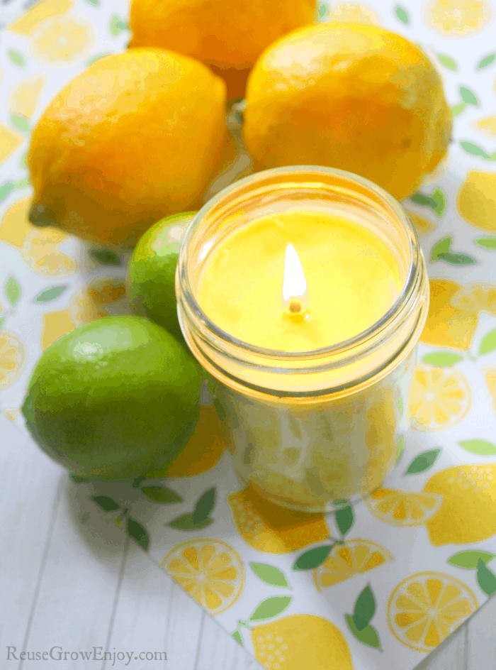 Yellow citrus soy candle with lemons and limes in background.