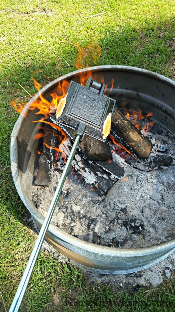 Pie iron being held over campfire.