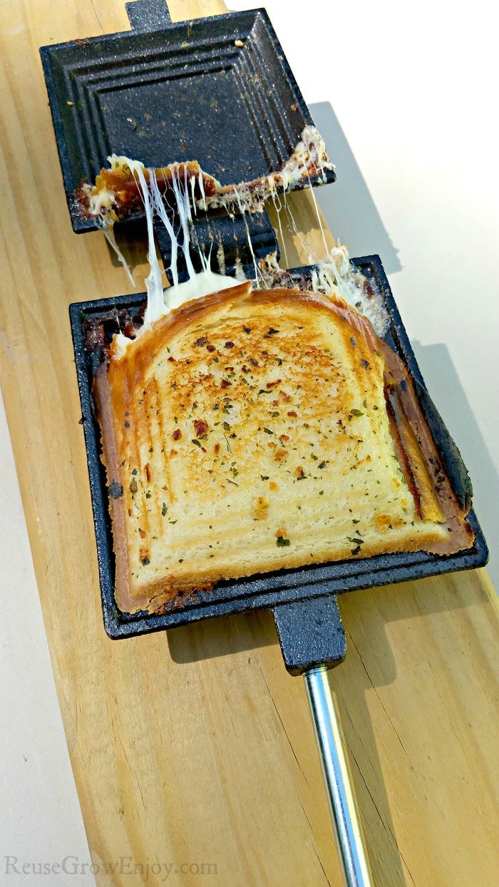 Cooked Garlic Grilled Cheese in pie iron laying on a board.