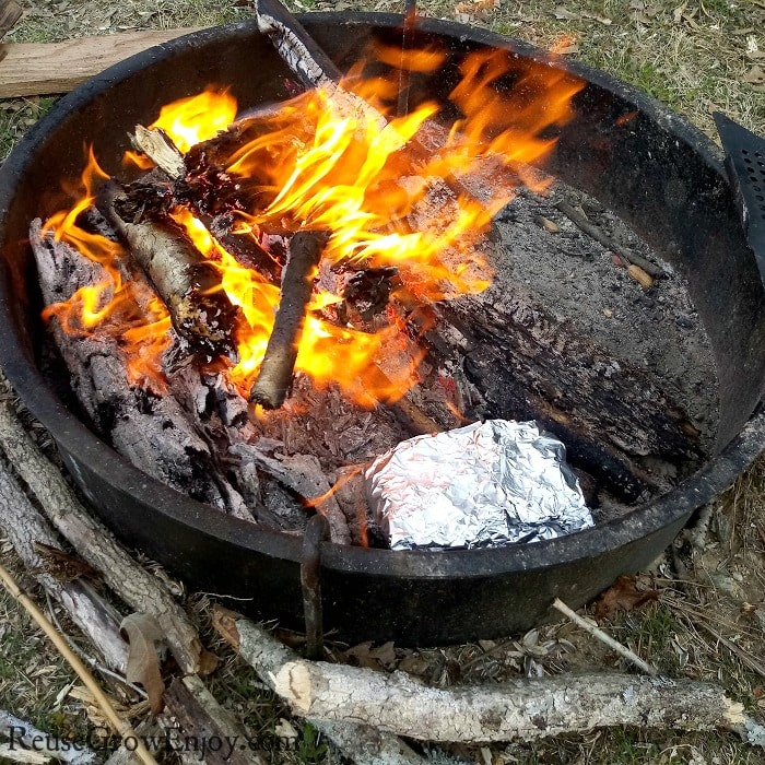 Blazing campfire with the foil pack salmon off to the side of the fire cooking.