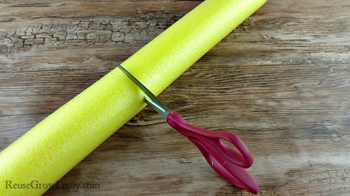 Scissors cutting a yellow pool noodle