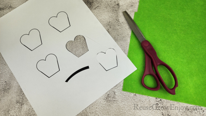 Scissors cutting out clover shapes from paper