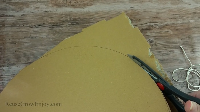 Scissors cutting cardboard into a round shape