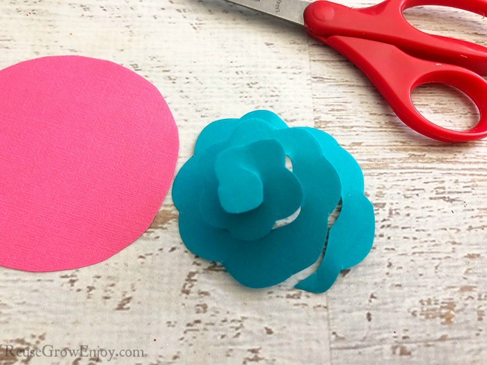 Pink and blue cardstock paper being cut into flower shapes.