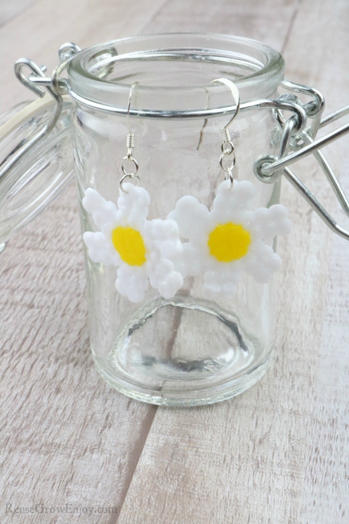 Finished daisy earrings hanging on side of glass jar