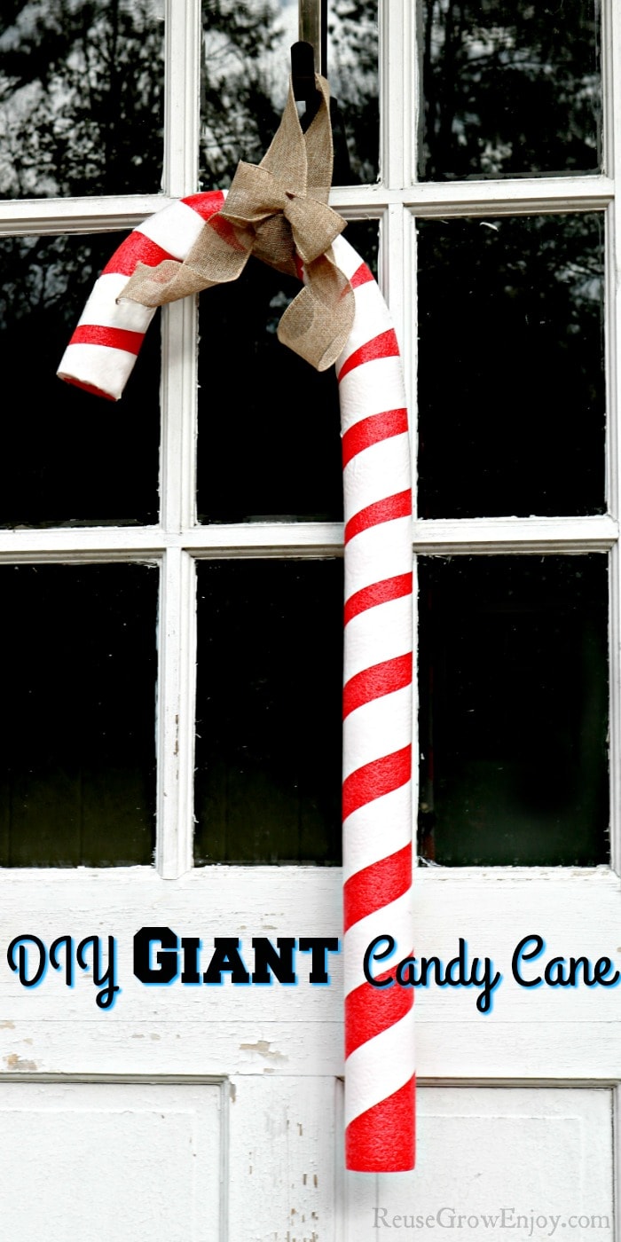 Giant candy cane hanging on a door with windows with text overlay at the bottom.