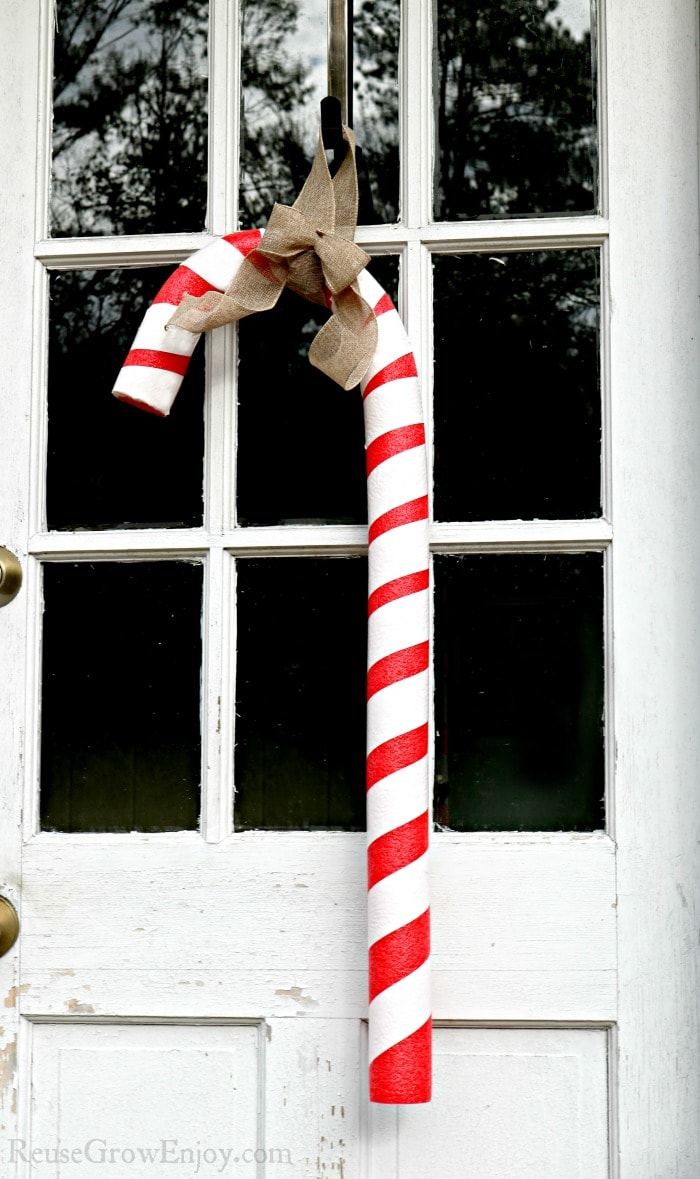 Giant candy cane hanging on white door with windows