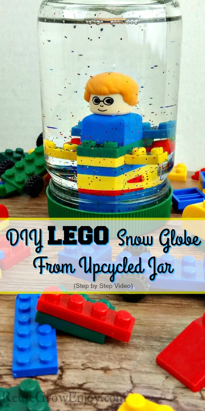 Small LEGOs all around with a upcycled mayo jar turned LEGO snow globe in the center that has LEGOs inside with glitter. Text overlay that says "DIY Lego Snow Globe From Upcycled Jar".