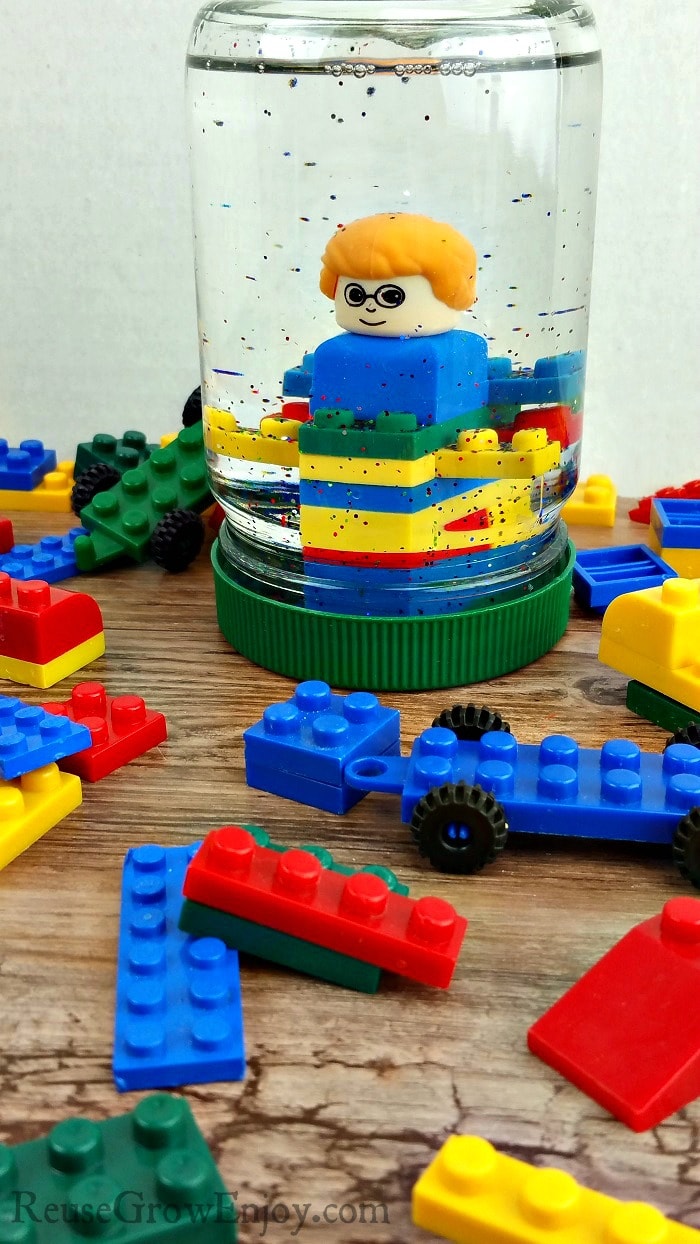 Small LEGOs all around with a upcycled mayo jar turned LEGO snow globe in the center that has LEGOs inside with glitter.