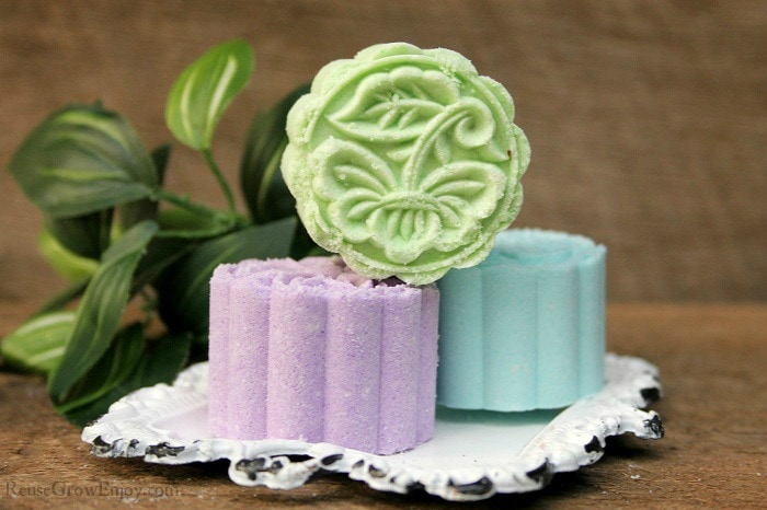 Three pressed bath bombs on a white tray with leaves in the background.