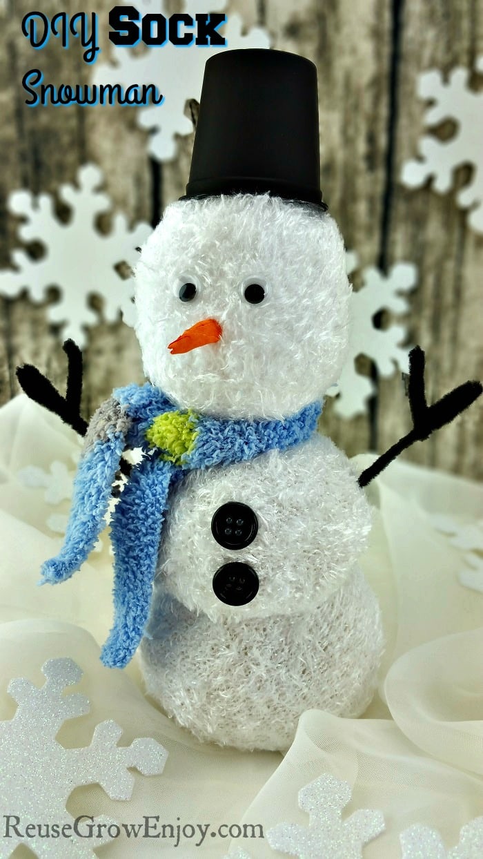 Sock Snowman with large fake snowflakes on wood background