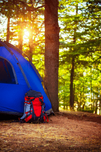 Blue tent in woods with red backpack