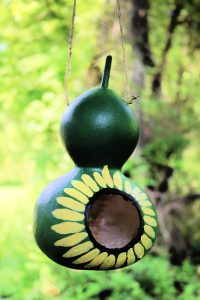 Painted gourd birdhouse hanging from tree