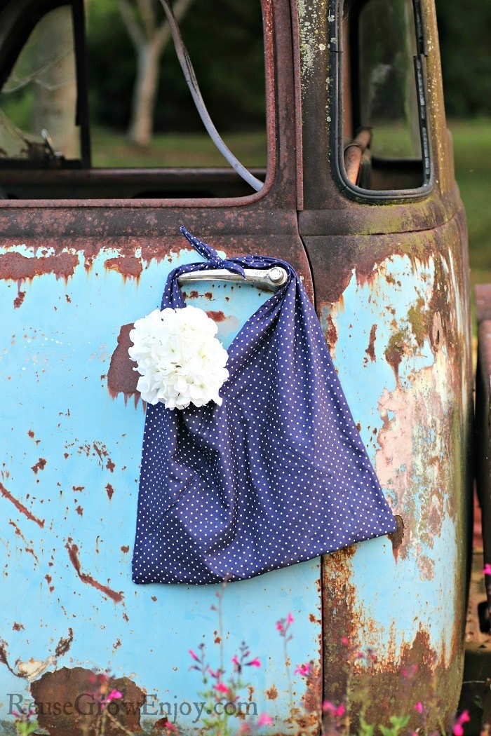 Blue with dots upcycled pillowcase bag hanging on doorknob of old rusty truck.