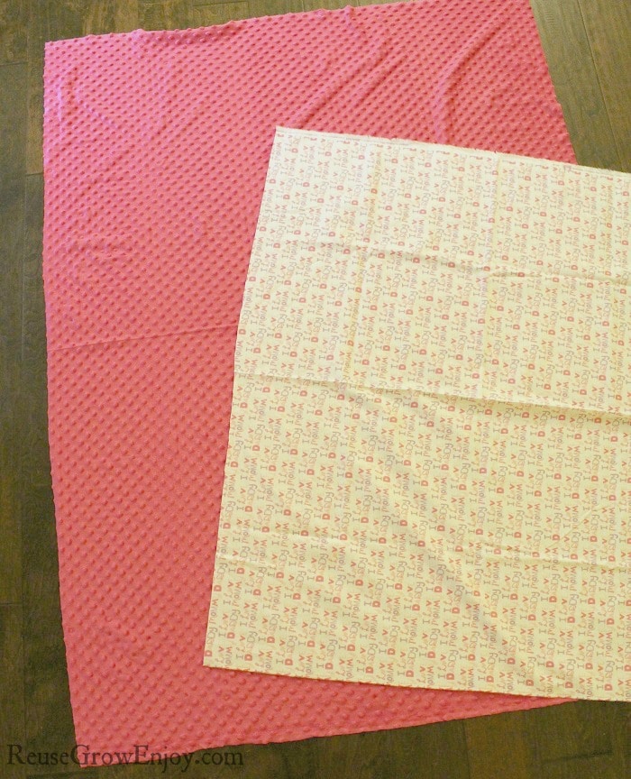 Two pieces of fabric. One white flannel with words the other pink minky dot.