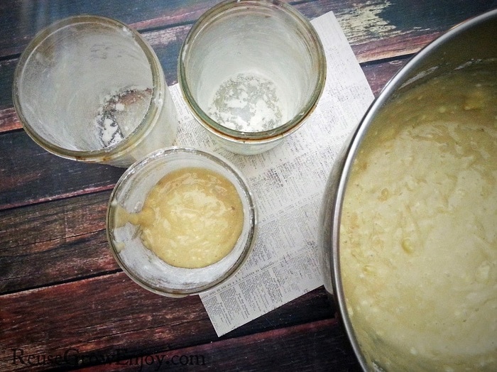 2 empty jars and one that is partly filled with bread mixture with the bowl of mixture off to the right side.