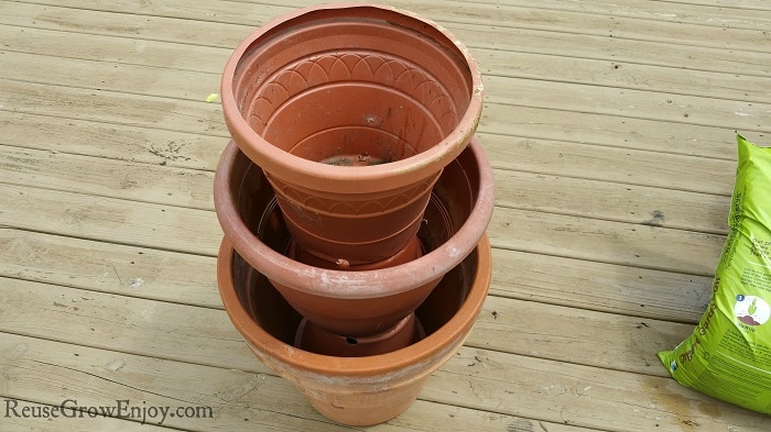 Different size flower pots stacked inside each other with another pot under each layer