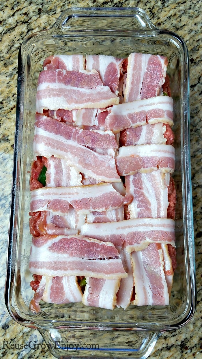 Bacon folded over the meatloaf in the glass loaf pan making up the bacon wrapped Whole30 meatloaf.
