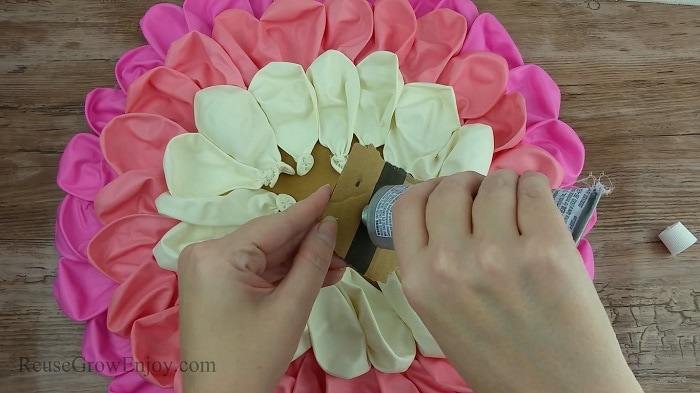 Hand gluing small piece of cardboard into the center of the balloons.