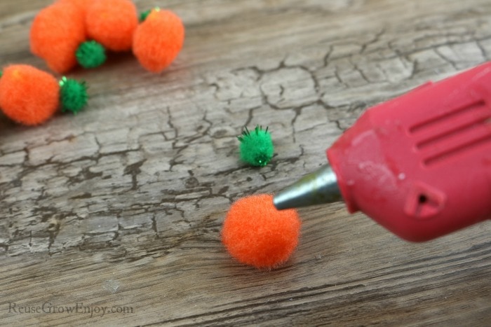 Glue green pompom on top of orange with hot glue gun.