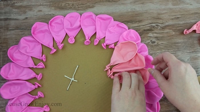 Hand gluing light pink balloons in place.
