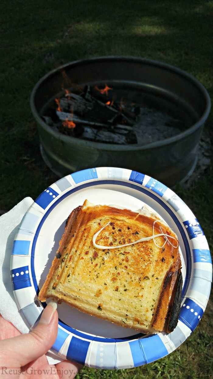 Grilled Cheese on plate with campfire in background.