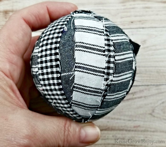 Hand holding ball covered in fabric strips