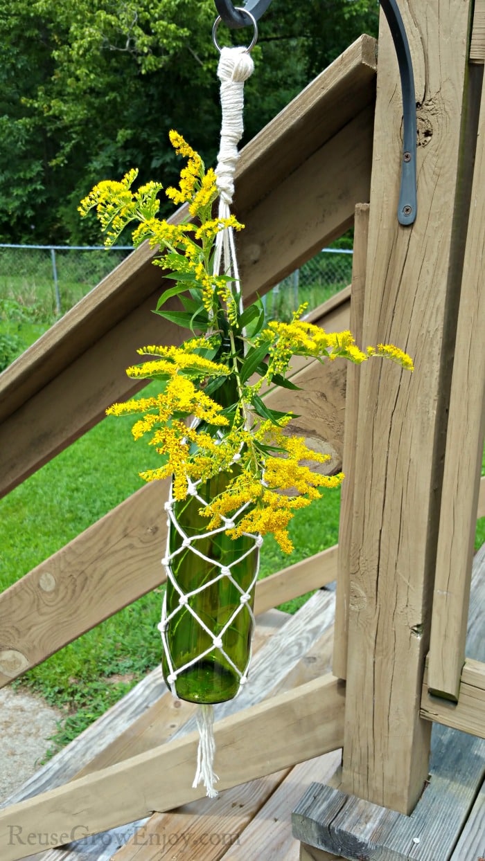 Hanging Wine Bottle Vase on a deck with yellow flowers in bottle