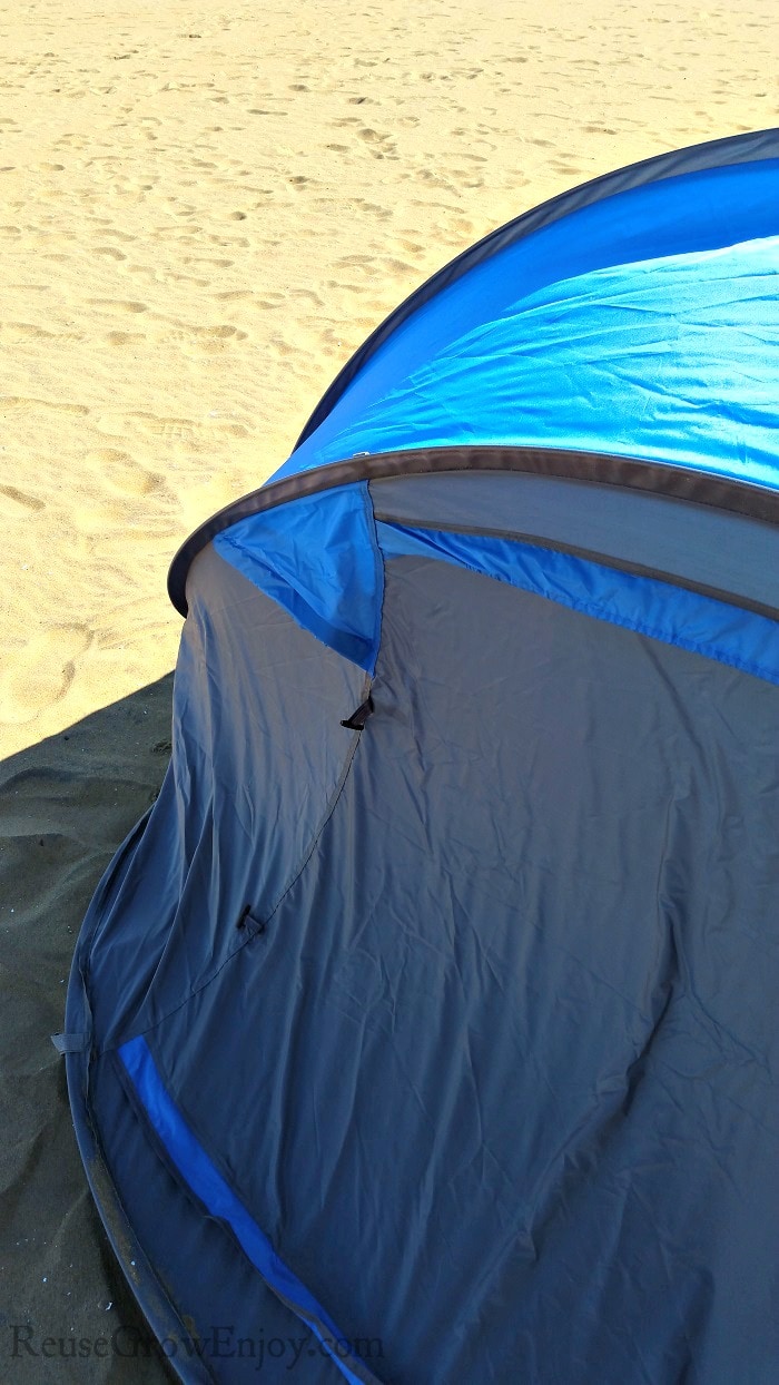 Blue tent set up on sand with nothing but sand behind it.