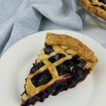 Slice of blueberry pie on white plate