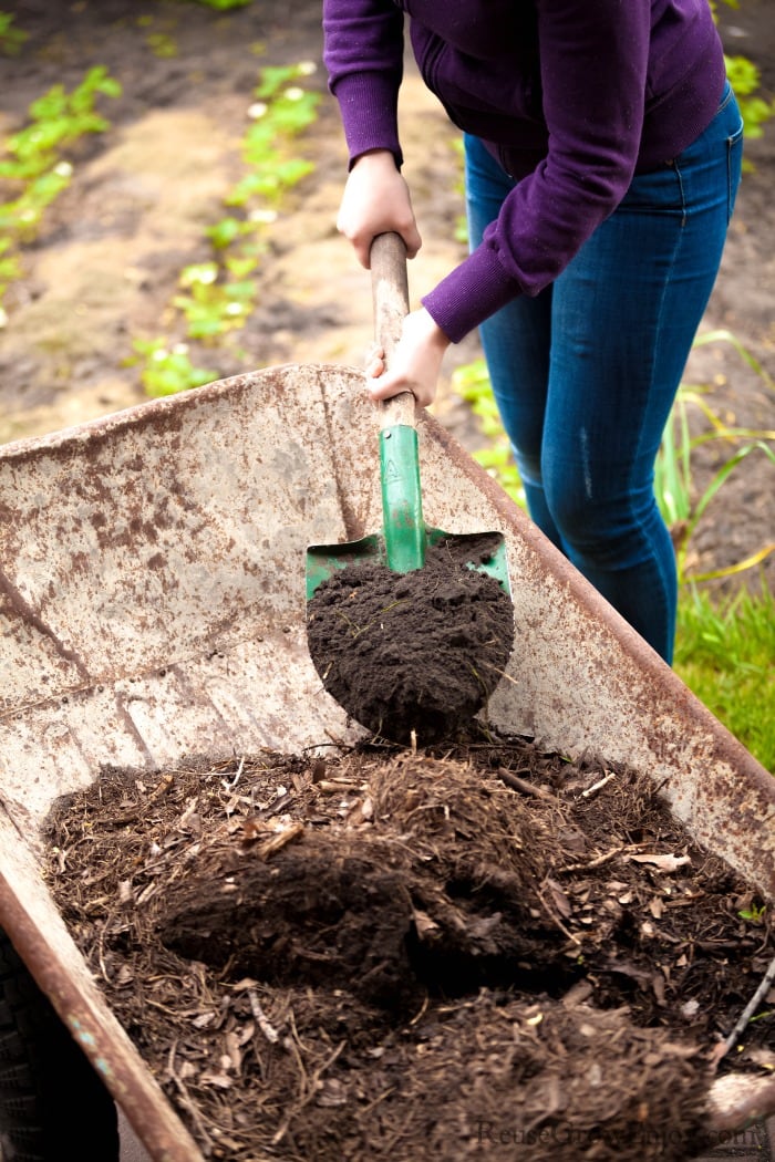 Person mixing compost in wheelbarrow 