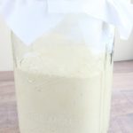 Mason jar of sourdough starter with white cloth on the top
