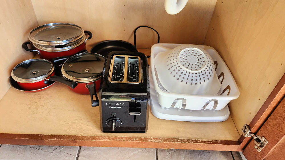 Pots and pans and dish drainer in cabinet