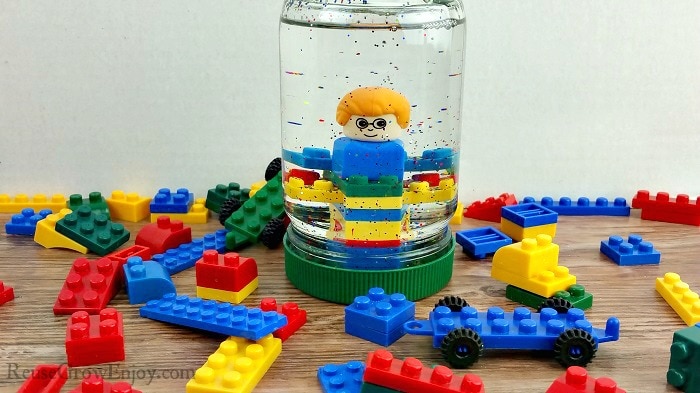 Small LEGOs all around with a upcycled mayo jar turned LEGO snow globe in the center that has LEGOs inside with glitter.