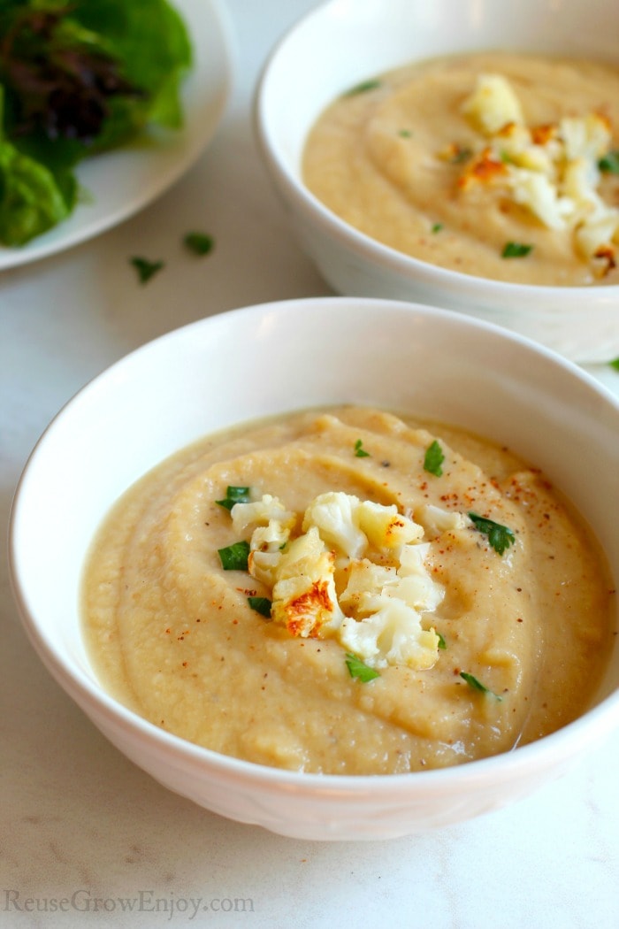 Two white bowls full of Low Carb Creamy Roasted Cauliflower Soup.